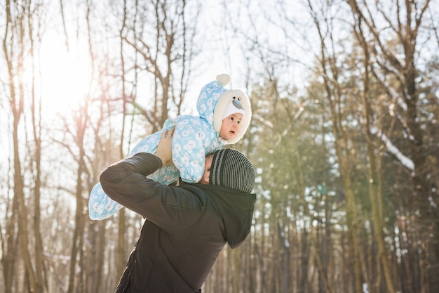 Glückliche Familie auf einem Winterspaziergang in der Natur. Papa erbricht Baby.