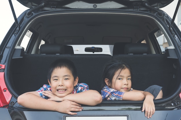 Glückliche Familie auf einer Autoreise, sitzen im Kofferraum des Autos