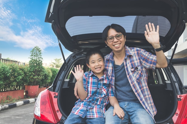 Glückliche Familie auf einer Autoreise, sitzen im Kofferraum des Autos