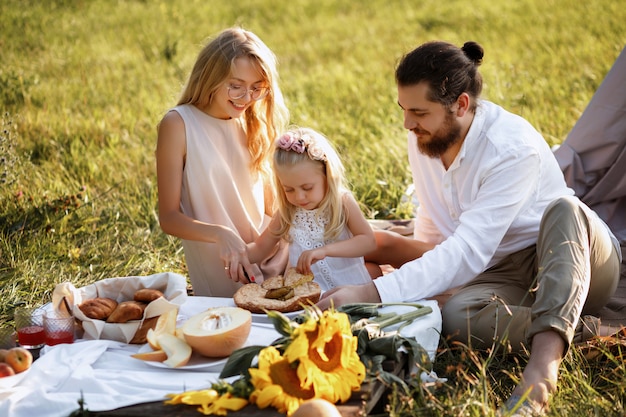 glückliche Familie auf Sommerpicknick schneidet Kuchen