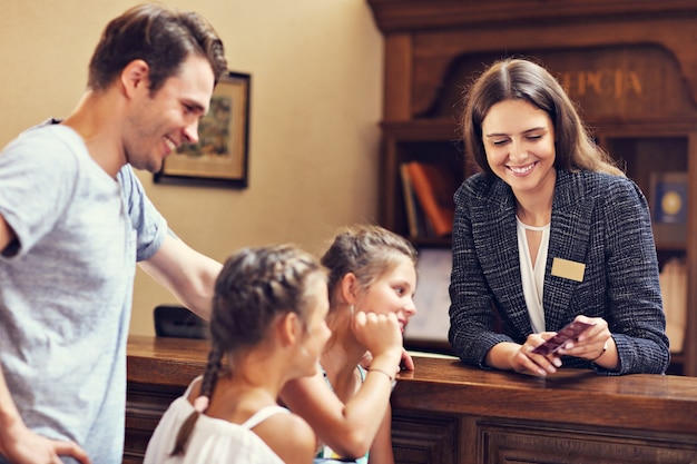 Glückliche Familie beim Einchecken im Hotel an der Rezeption