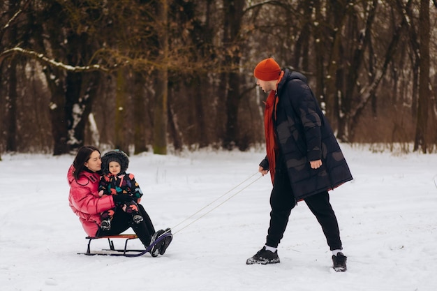 Glückliche Familie beim Schlittenfahren im Winterwald. Hochwertiges Foto