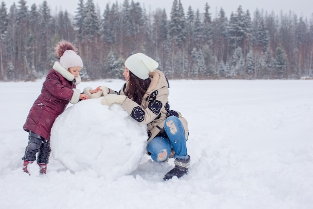 Glückliche Familie der Mutter und des Kindes genießen schneebedeckten Tag des Winters