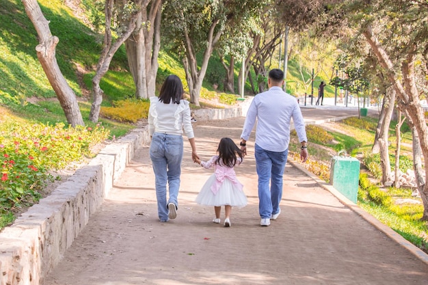 Glückliche Familie, die am Nachmittag Händchen haltend durch den Park spaziert