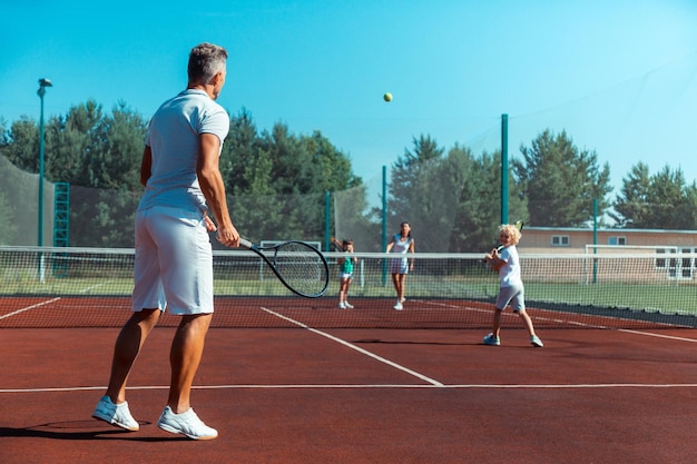 Glückliche Familie, die am Wochenende Sport liebt und Tennis spielt