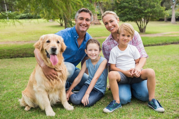 Glückliche Familie, die an der Kamera mit ihrem Hund lächelt