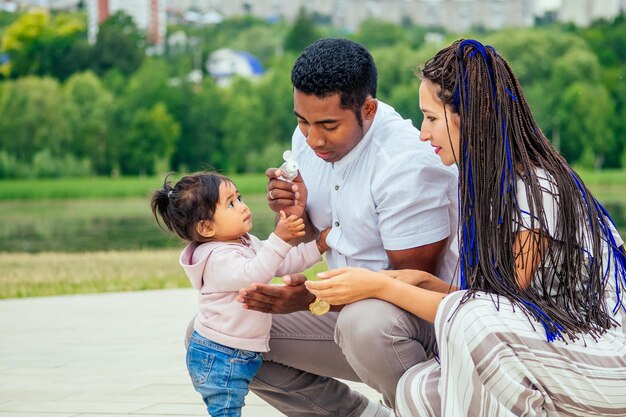 Glückliche Familie, die antibakterielles Handsanitizer-Gel auf die Hände der Tochter aufträgt