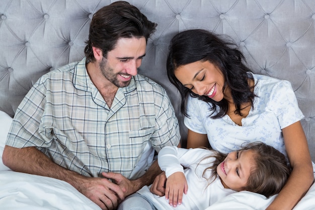 Glückliche Familie, die auf Bett spielt