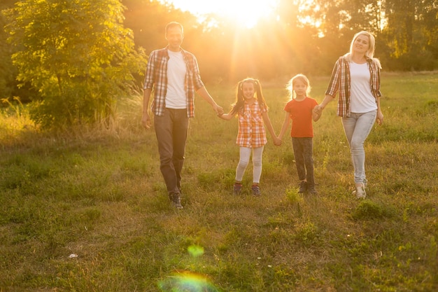 Glückliche Familie, die auf dem Feld spazieren geht und den Sonnenuntergang betrachtet