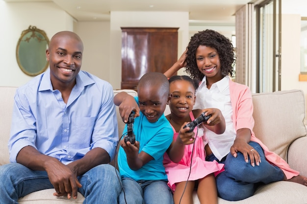 Glückliche Familie, die auf der Couch Videospiele spielend sich entspannt