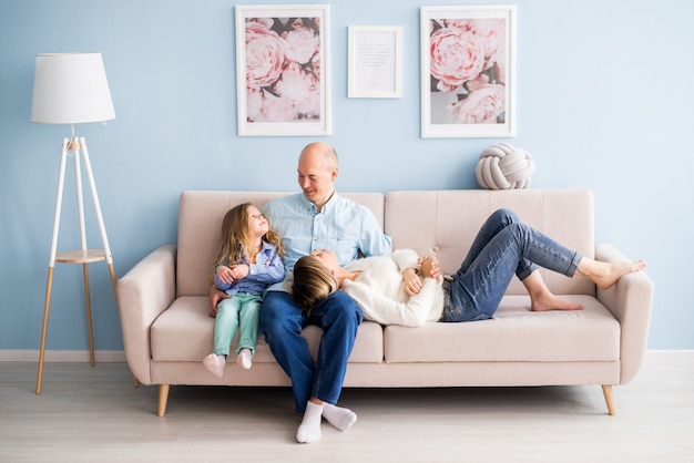 Glückliche Familie, die auf der Couch zu Hause sitzt