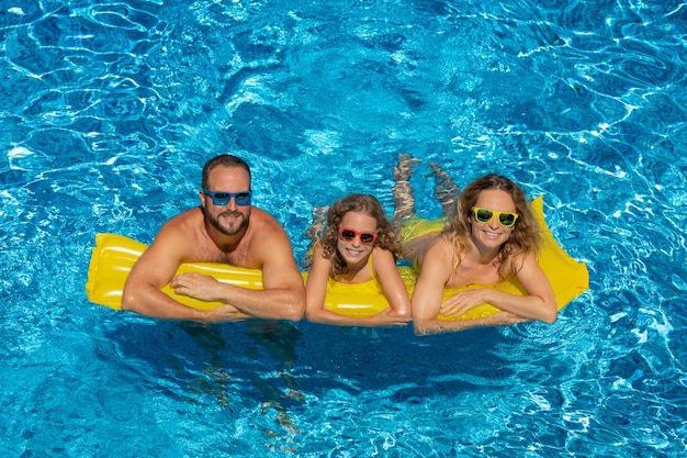 Glückliche Familie, die auf gelber Matratze im Außenpool schwimmt Menschen, die Spaß im Sommerurlaub haben Gesundes Lifestyle-Konzept