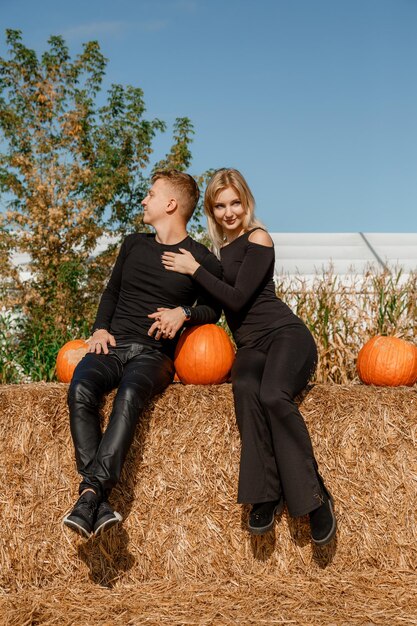 Foto glückliche familie, die auf heuballen sitzt und kürbisse auf dem markt im freien hält. herbstzeit.