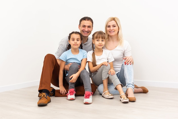 Glückliche Familie, die auf Holzboden sitzt. Vater, Mutter und Kind, die zusammen Spaß haben. Umzugstag, neues Wohnkonzept