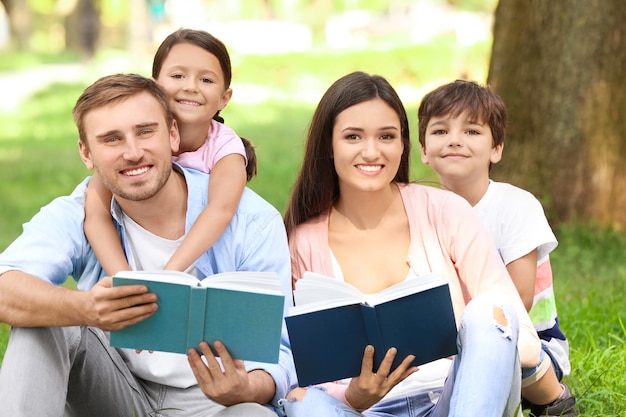 Glückliche Familie, die Bücher im Park liest