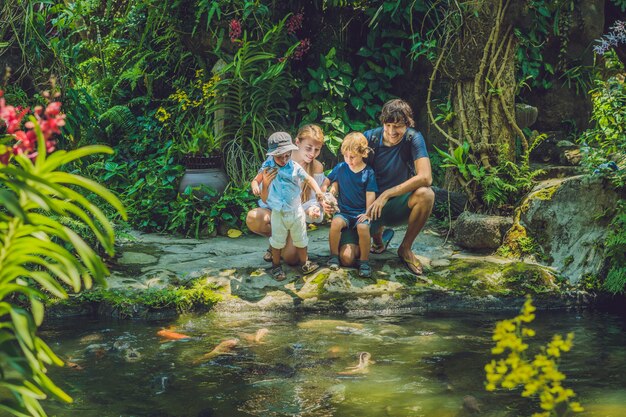 Glückliche Familie, die bunten Wels im tropischen Teich füttert