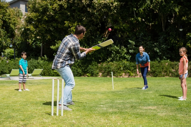 Glückliche Familie, die Cricket im Park spielt