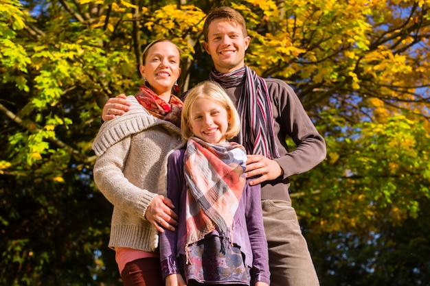 Glückliche Familie, die draußen auf Gras im Herbst sitzt