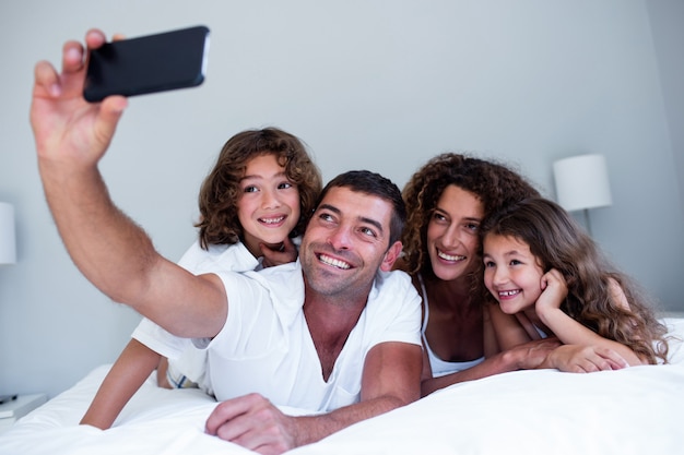 Glückliche familie, die ein selfie auf bett nimmt