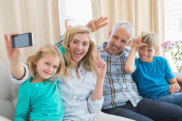 Glückliche Familie, die ein selfie auf Couch nimmt