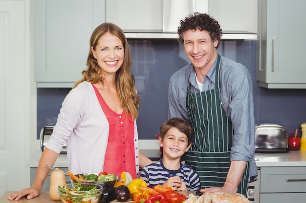 Glückliche Familie, die einen Gemüsesalat zubereitet