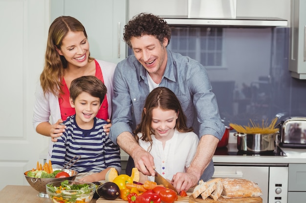 Glückliche Familie, die einen Gemüsesalat zubereitet