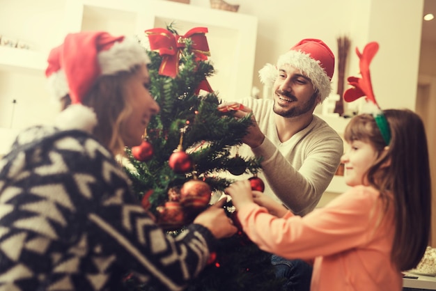 Glückliche Familie, die einen Weihnachtsbaum verziert