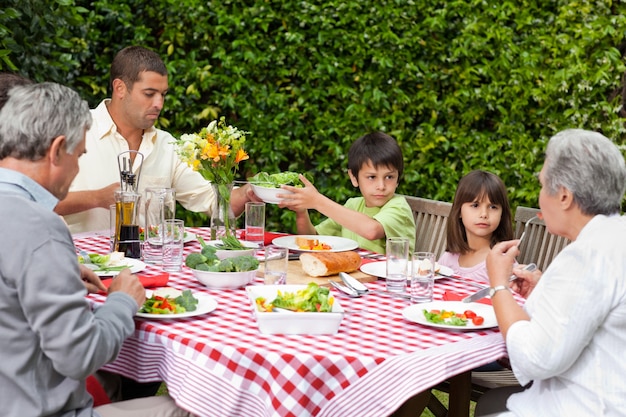 Glückliche Familie, die im Garten isst