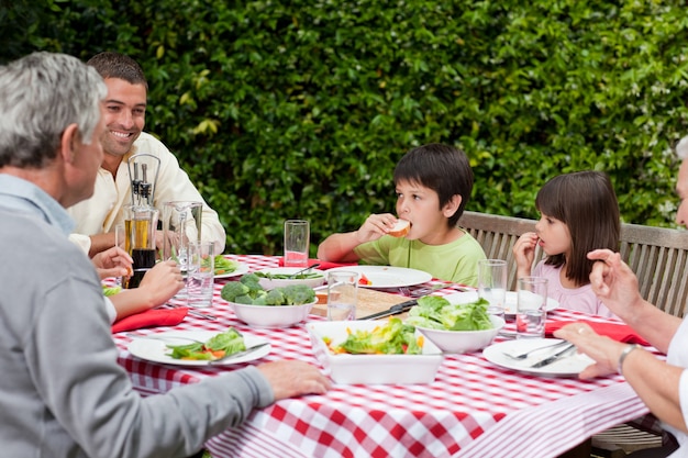 Glückliche Familie, die im Garten isst