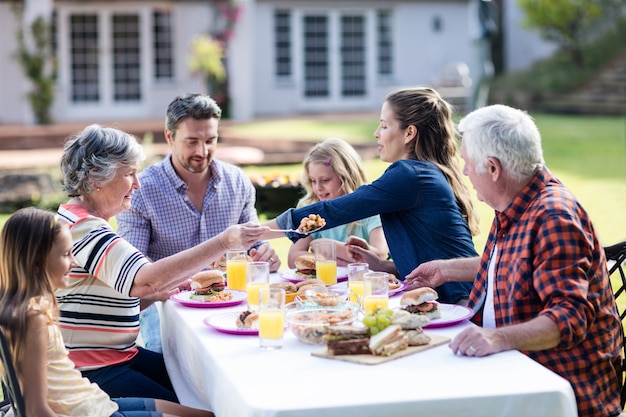 Glückliche Familie, die im Garten zu Mittag isst