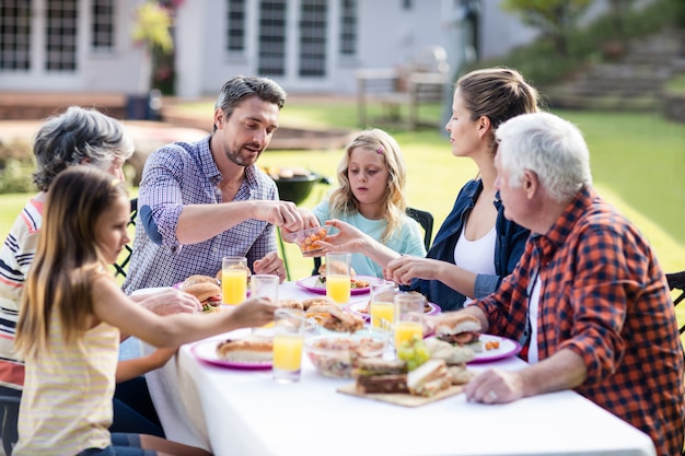 Glückliche Familie, die im Garten zu Mittag isst