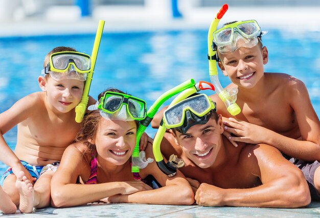 Glückliche Familie, die im Schwimmbad spielt. Sommerferienkonzept