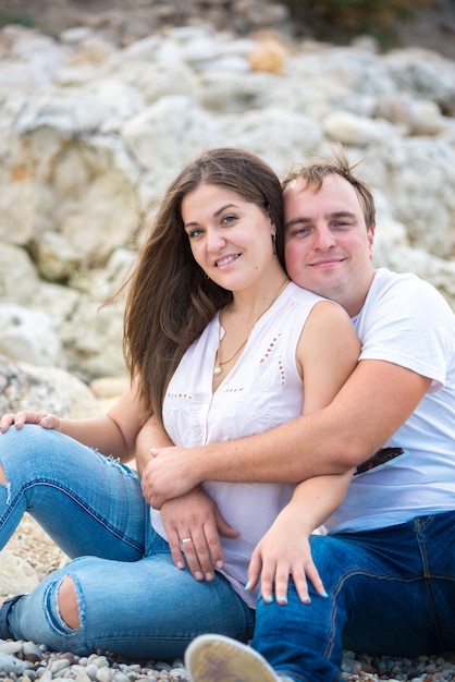 Glückliche Familie, die im Sommer auf den Steinen vor dem Meer sitzt.