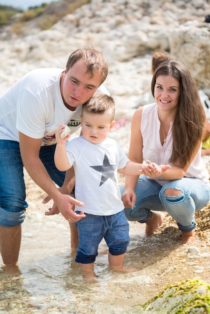 Glückliche Familie, die im Sommer auf einem Holzponton vor dem Meer steht