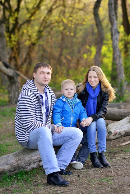 Glückliche Familie, die im Wald auf einem umgestürzten Baumstamm sitzt