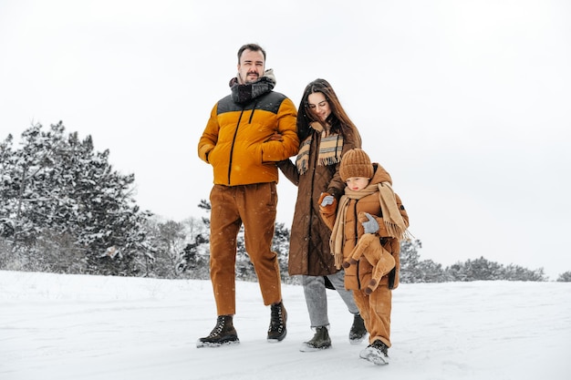 Glückliche Familie, die im Winter draußen im Schnee spazieren geht