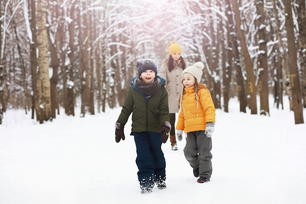 Glückliche Familie, die im Winter draußen im Schnee spielt und lacht. Wintertag im Stadtpark.