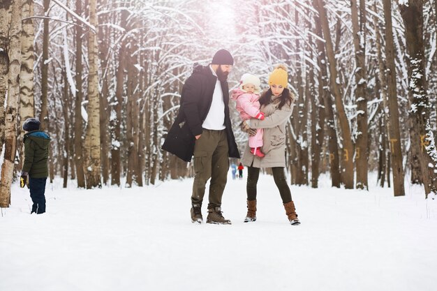 Glückliche Familie, die im Winter draußen im Schnee spielt und lacht. Wintertag im Stadtpark.