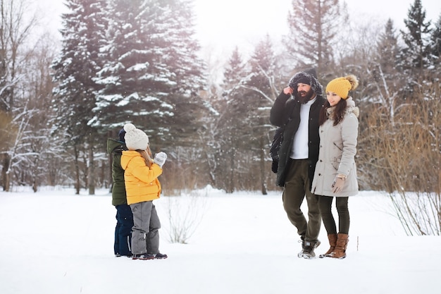 Glückliche Familie, die im Winter draußen im Schnee spielt und lacht. Wintertag im Stadtpark.