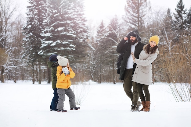 Glückliche Familie, die im Winter draußen im Schnee spielt und lacht. Wintertag im Stadtpark.