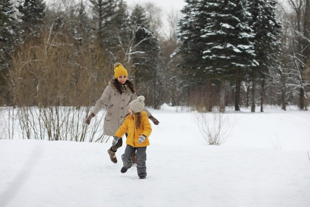 Glückliche Familie, die im Winter draußen im Schnee spielt und lacht. Wintertag im Stadtpark.