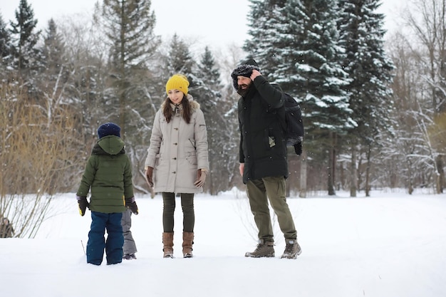 Glückliche Familie, die im Winter draußen im Schnee spielt und lacht. Wintertag im Stadtpark.