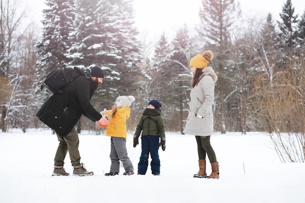 Glückliche Familie, die im Winter draußen im Schnee spielt und lacht. Wintertag im Stadtpark.