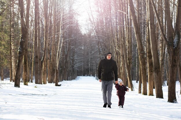 Glückliche Familie, die im Winter draußen im Schnee spielt und lacht. Wintertag im Stadtpark.