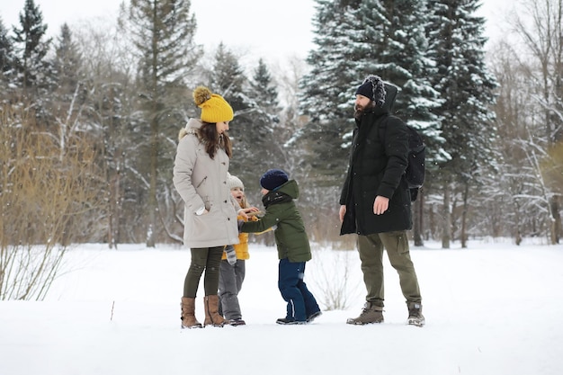 Glückliche Familie, die im Winter draußen im Schnee spielt und lacht. Wintertag im Stadtpark.