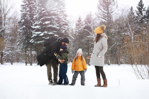 Glückliche Familie, die im Winter draußen im Schnee spielt und lacht. Wintertag im Stadtpark.