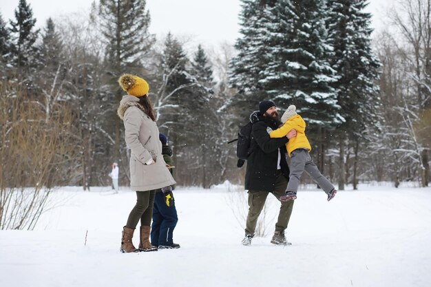 Glückliche Familie, die im Winter draußen im Schnee spielt und lacht. Wintertag im Stadtpark.