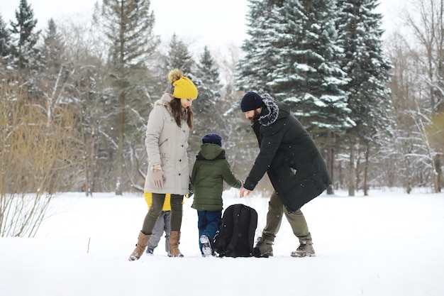 Glückliche Familie, die im Winter draußen im Schnee spielt und lacht. Wintertag im Stadtpark.