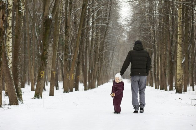 Glückliche Familie, die im Winter draußen im Schnee spielt und lacht. Wintertag im Stadtpark.