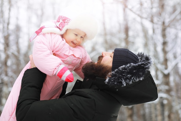 Glückliche Familie, die im Winter draußen im Schnee spielt und lacht. Wintertag im Stadtpark.